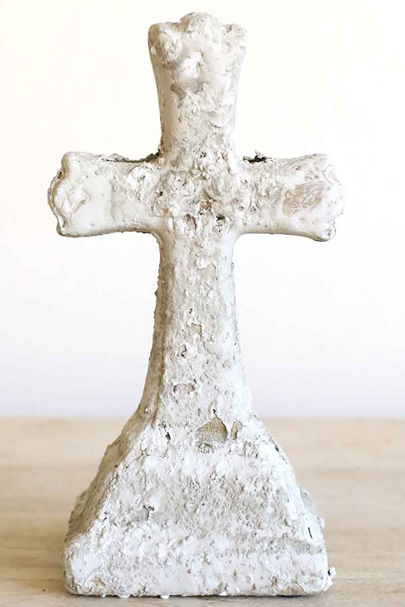 Decorative cross with a textured surface on a light wooden surface.