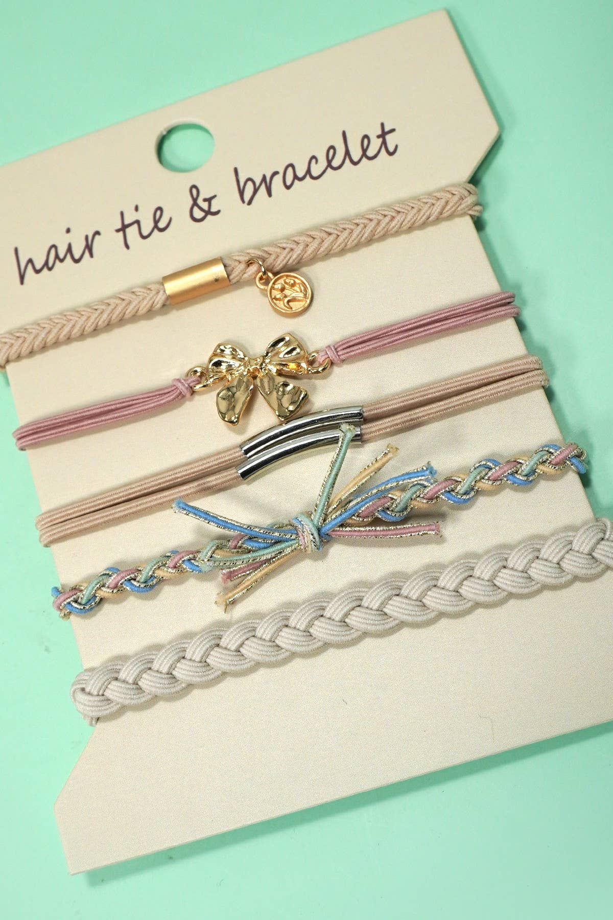 Set of hair ties and bracelets on a display card with a green background