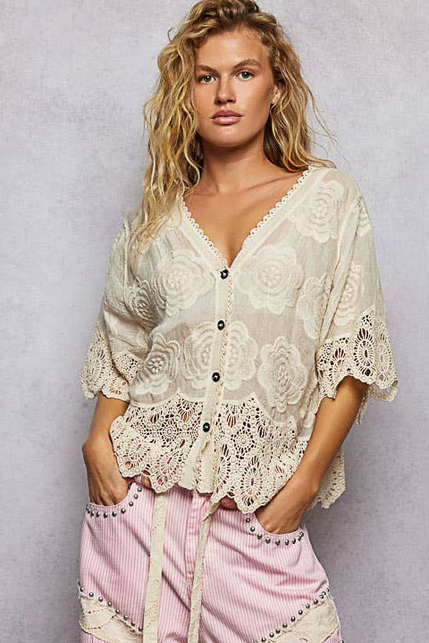 Woman wearing a stylish outfit with a lace top and pink pants against a plain background