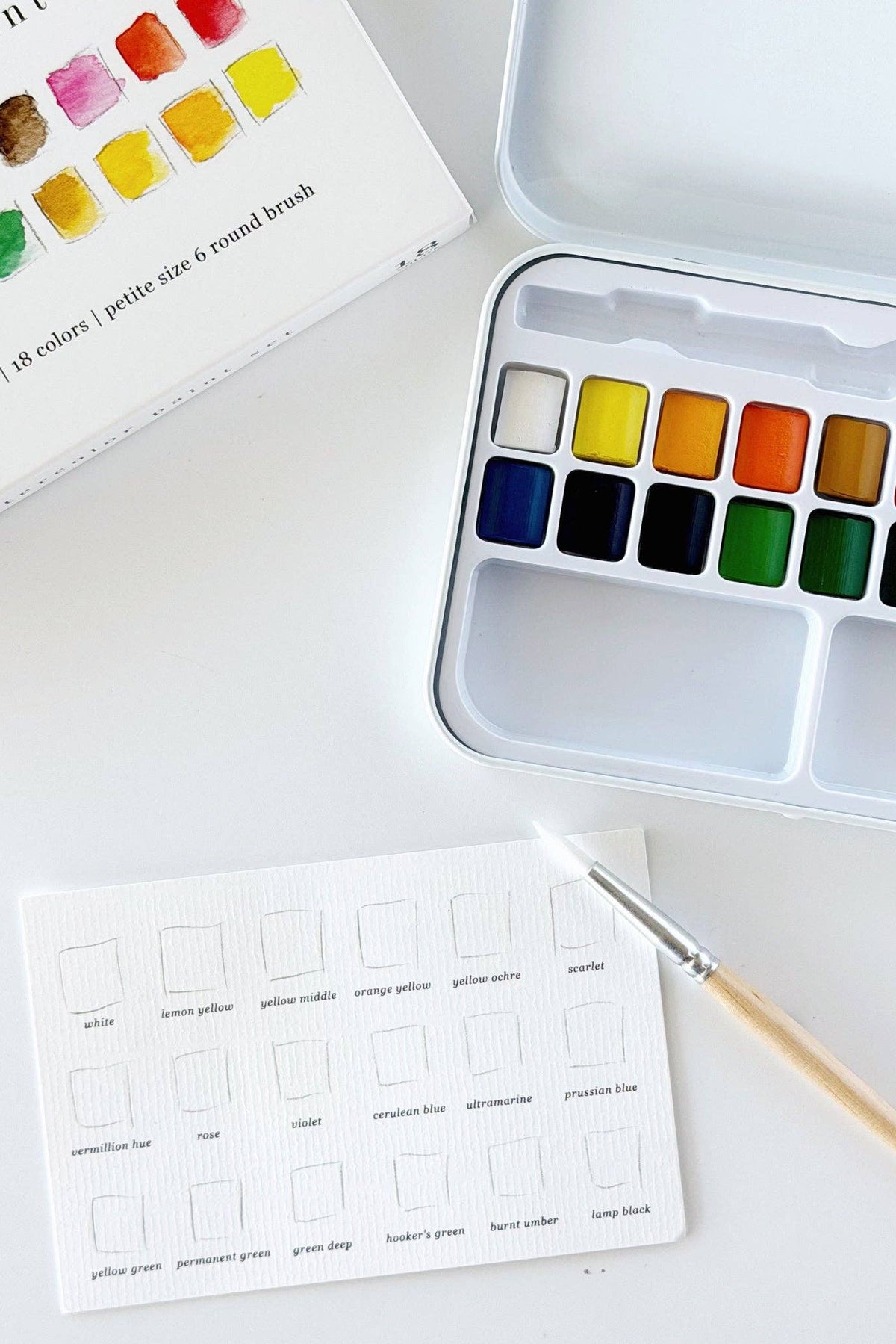 Watercolor paint set with color swatches on a white surface