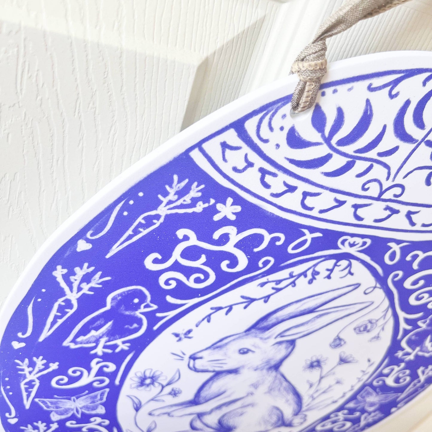 Decorative door hanger with blue and white intricate patterns on a light wooden surface