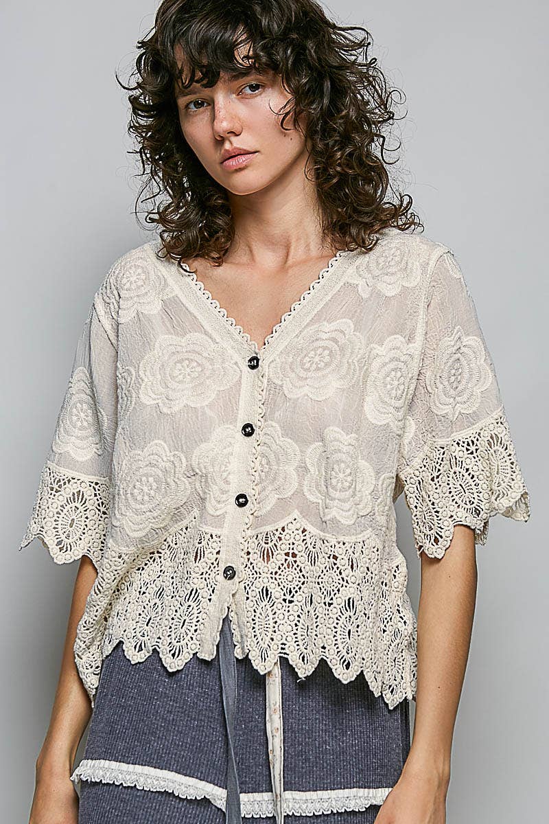 Woman wearing a lace blouse with black buttons on a gray background