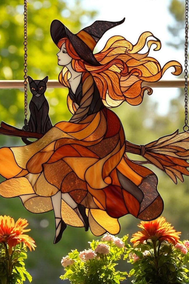 Stained glass look window hanging of a witch on a broomstick with a cat, surrounded by flowers.
