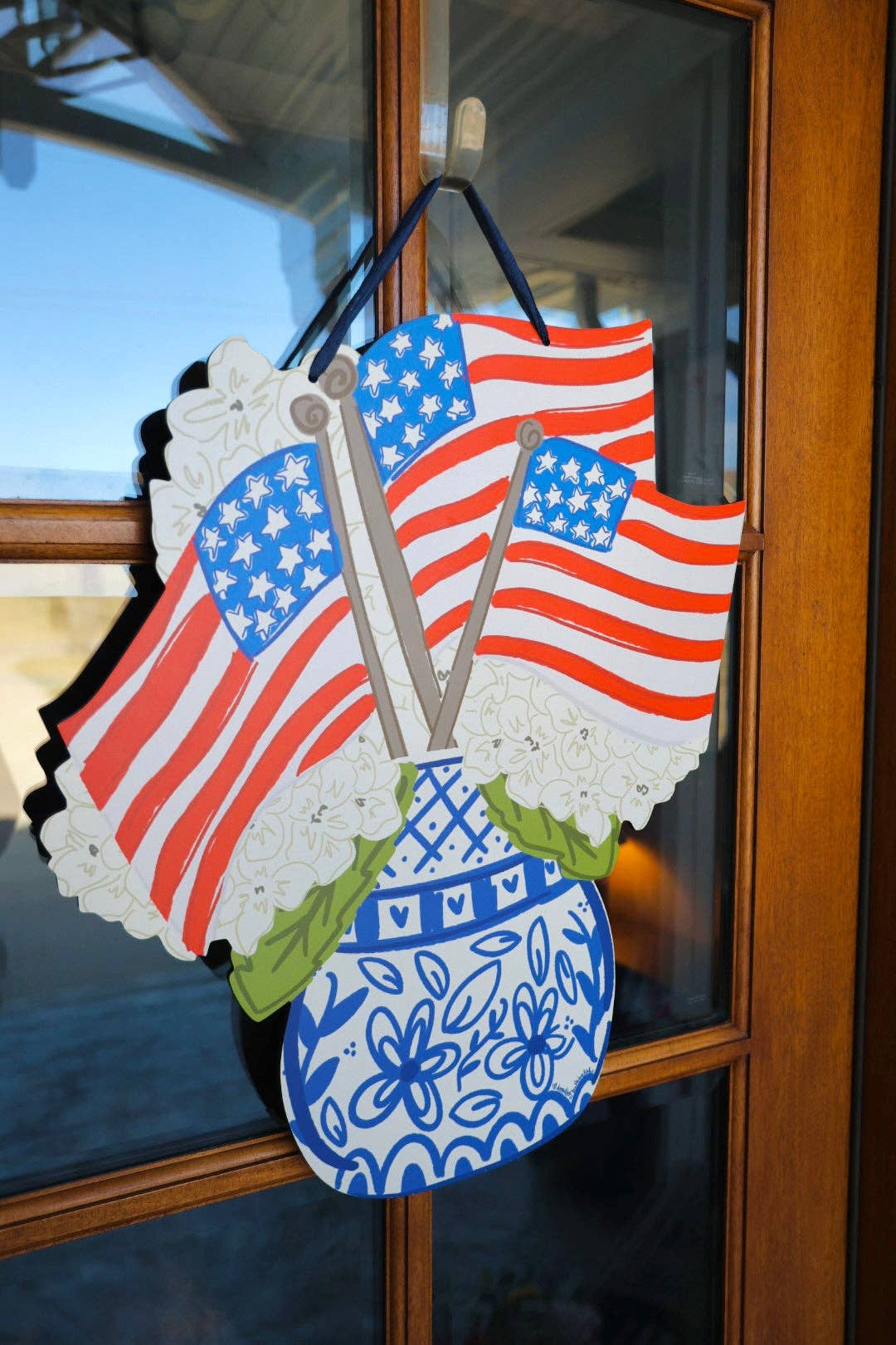 Decorative door hanger with American flag design on a glass door.
