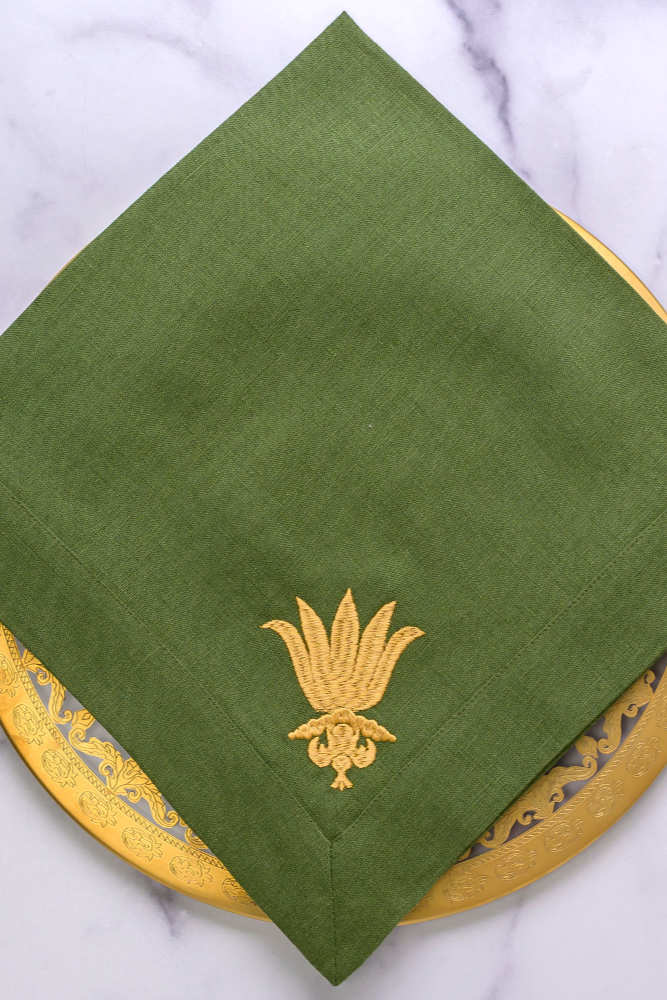 Green napkin with gold embroidery on a marble surface