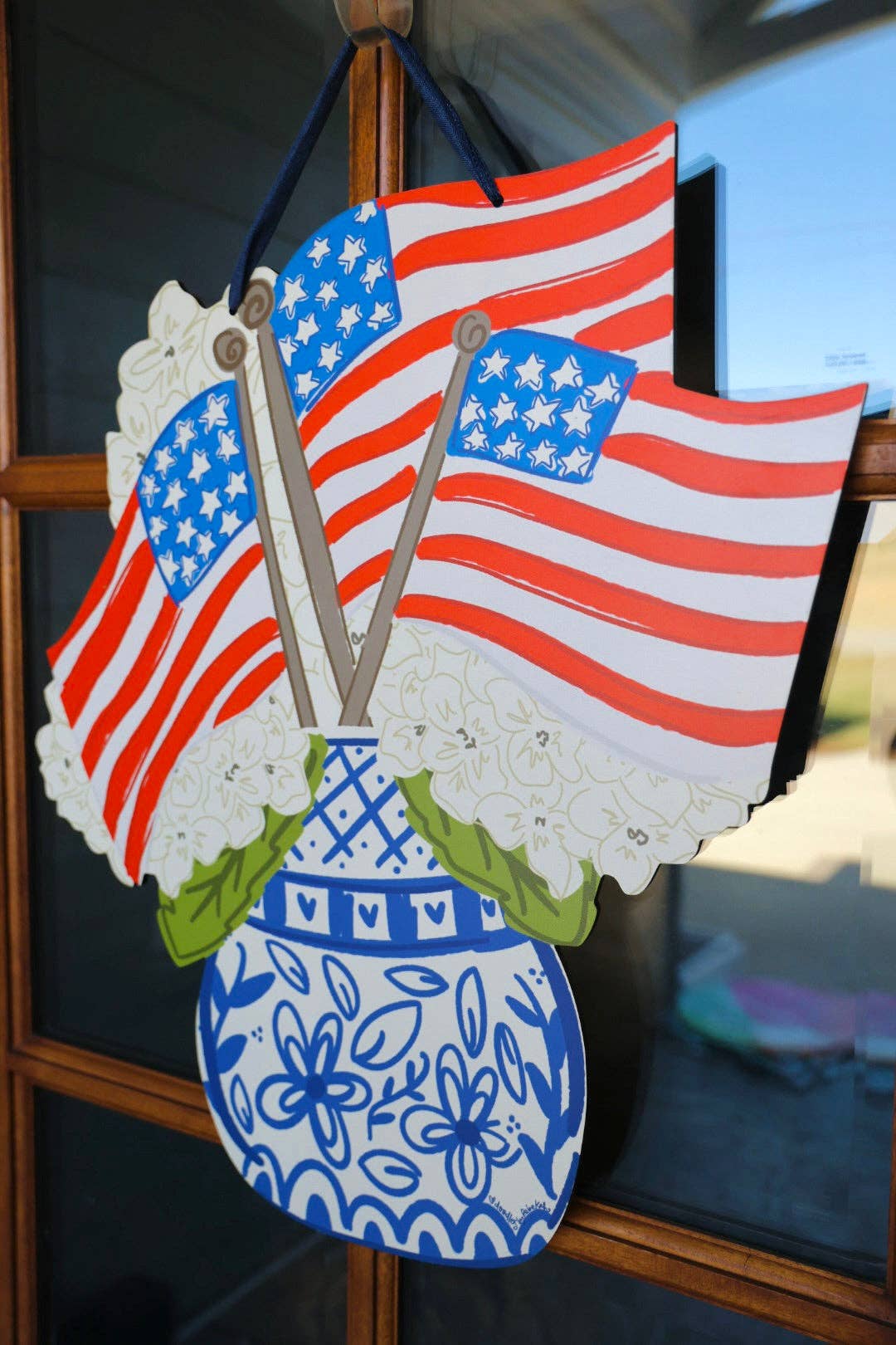 Decorative wall hanging with American flags and a blue vase.