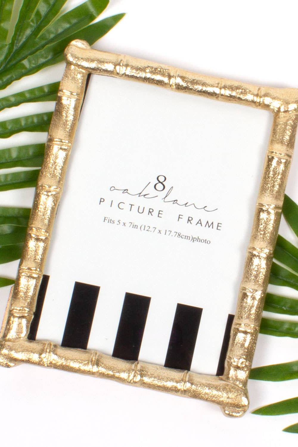 Gold picture frame with black and white striped design on a white background with green leaves.