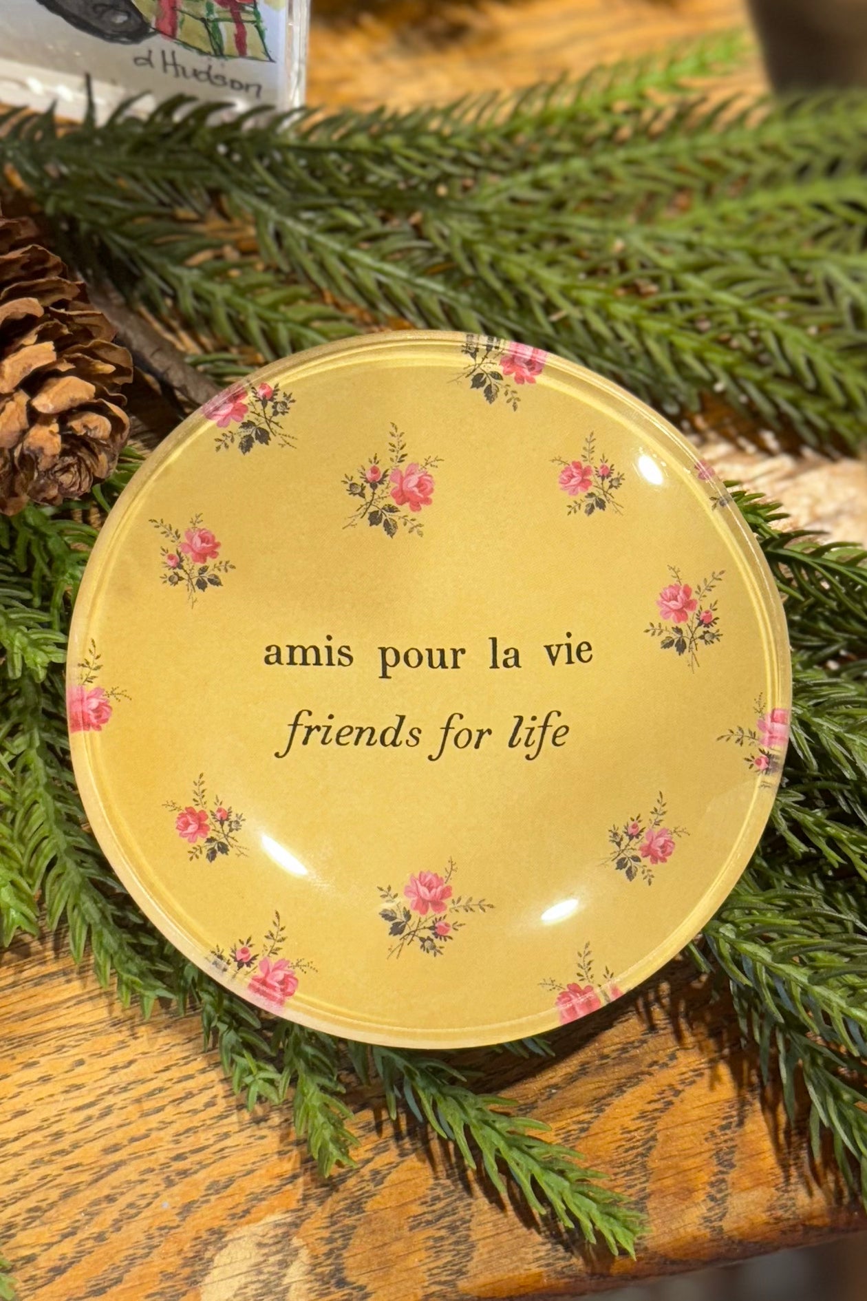 Decorative plate with floral designs and text on a green leafy background