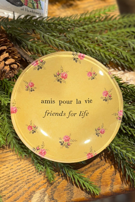 Decorative plate with floral designs and text on a green leafy background