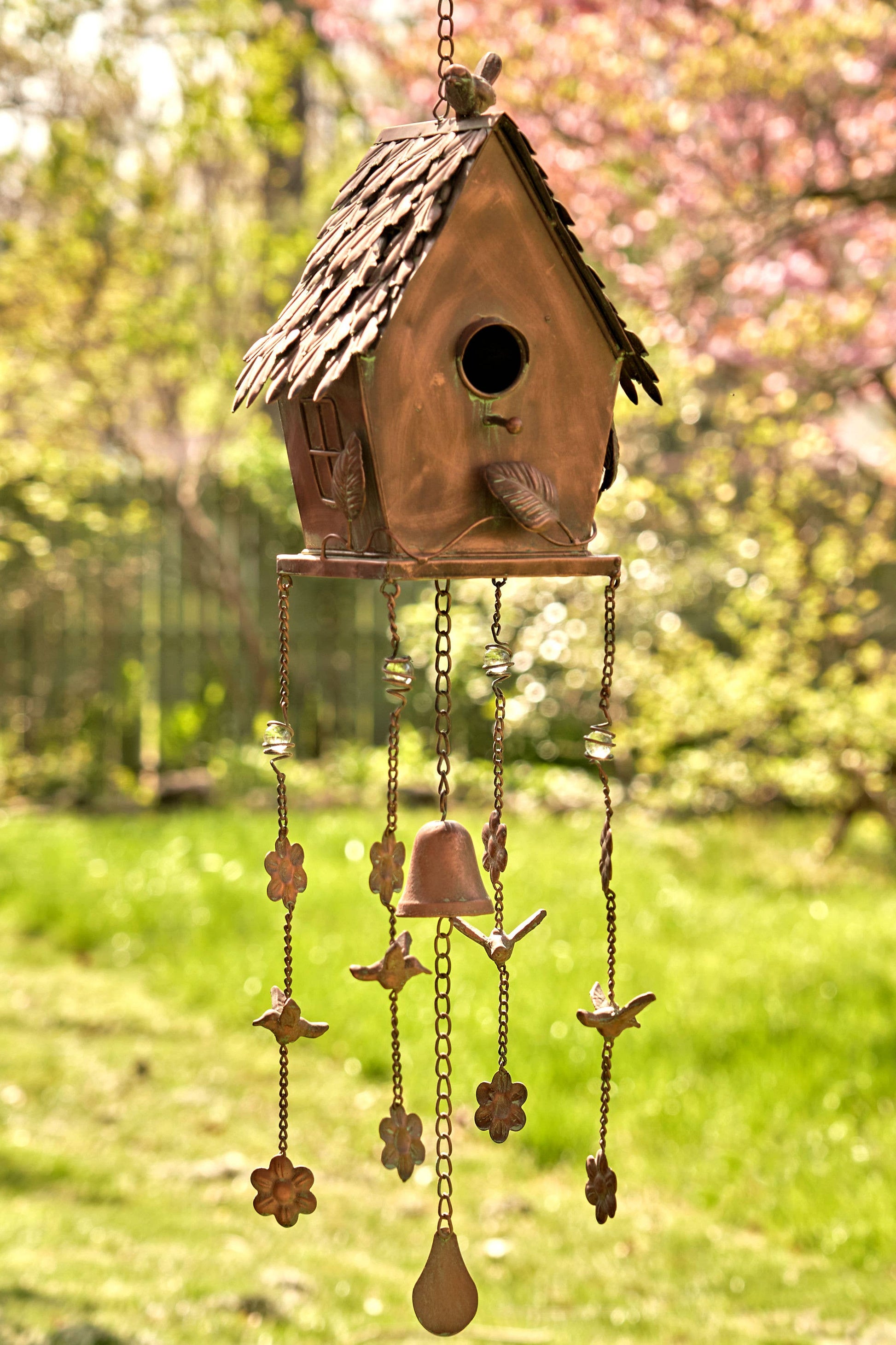 Decorative birdhouse with hanging charms in a garden setting