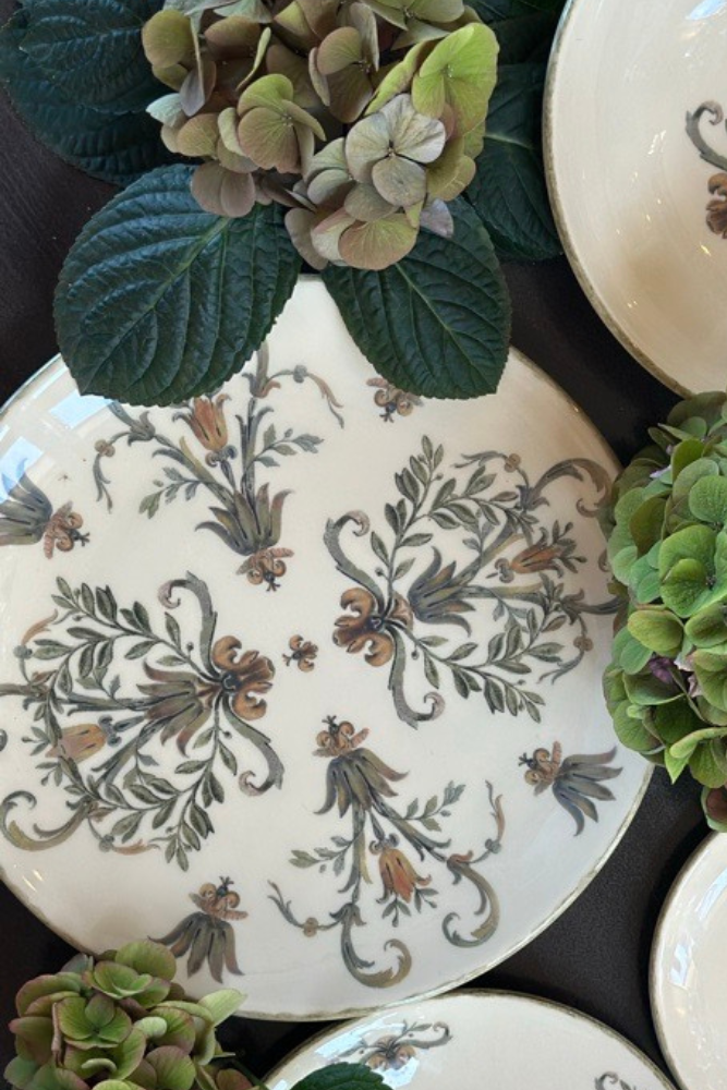 Decorative plates with floral patterns and green hydrangeas on a dark surface