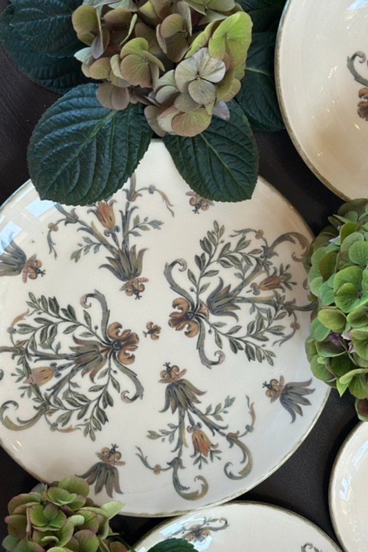 Decorative plates with floral patterns and green hydrangeas on a dark surface
