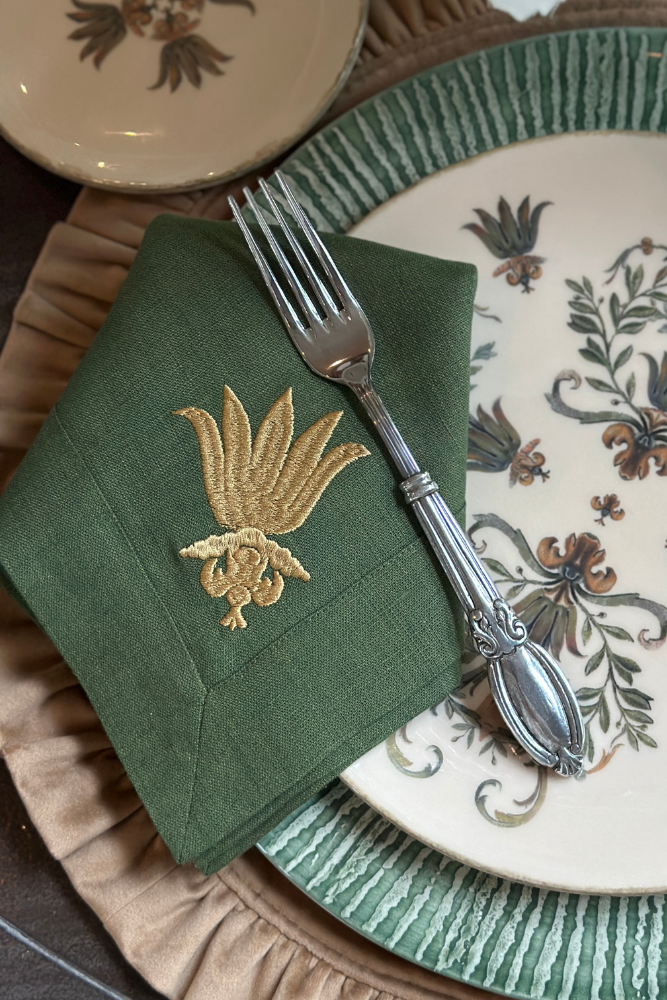 Decorative plate with floral patterns, green napkin, and silver fork on a textured surface.