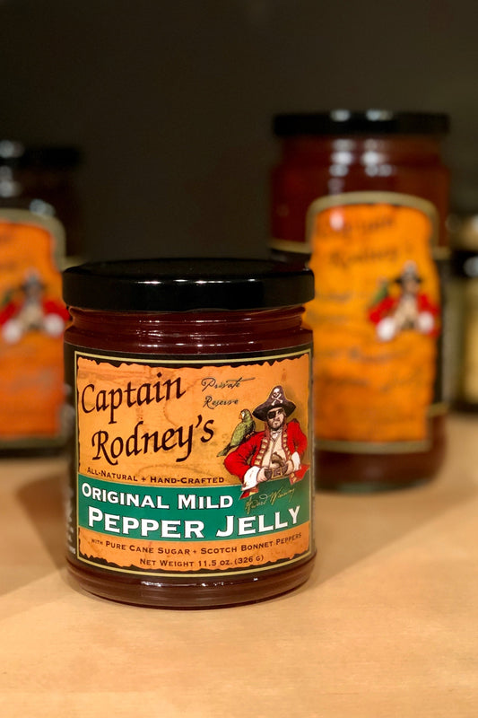 Jars of Captain Rodney's Original Mild Pepper Jelly on a wooden surface with blurred background