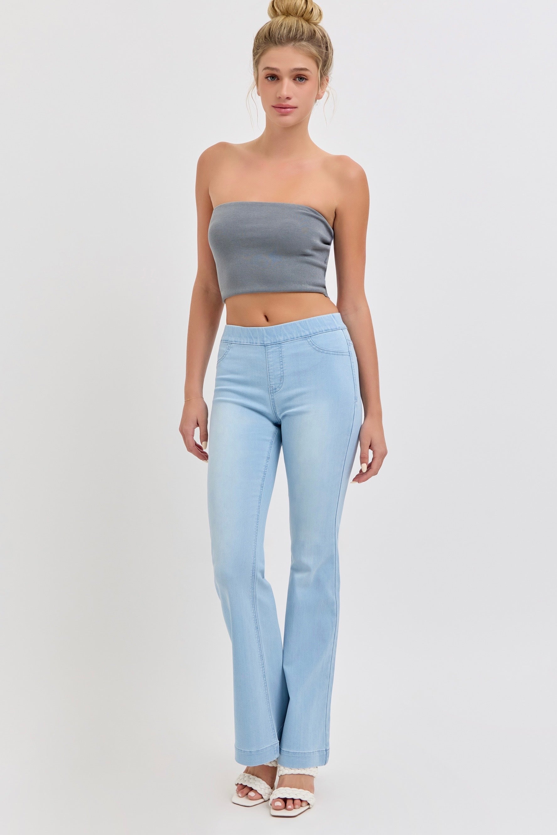 Woman wearing a gray strapless top and light blue Cello jeans on a white background