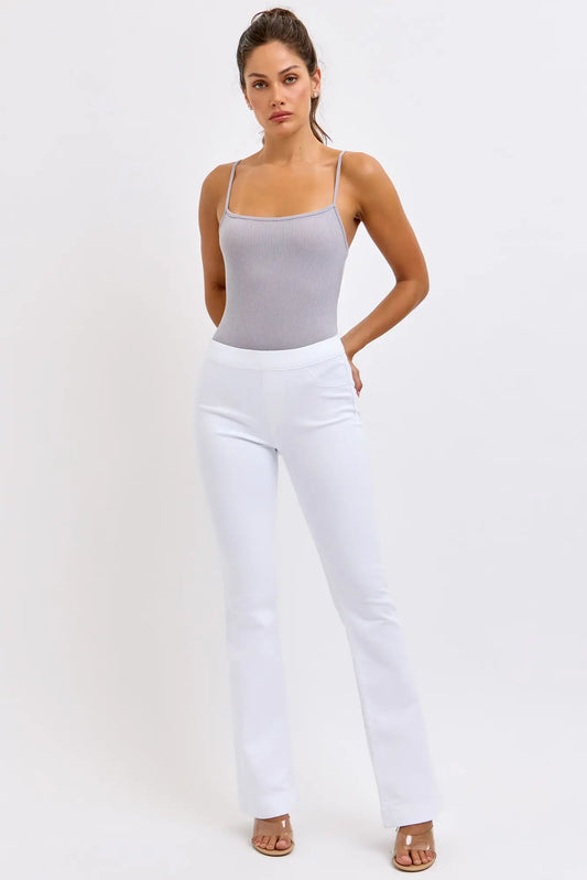 Woman wearing a gray tank top and white cello pants on a white background