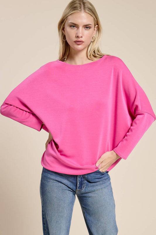 Woman wearing a bright pink sweater and blue jeans on a beige background