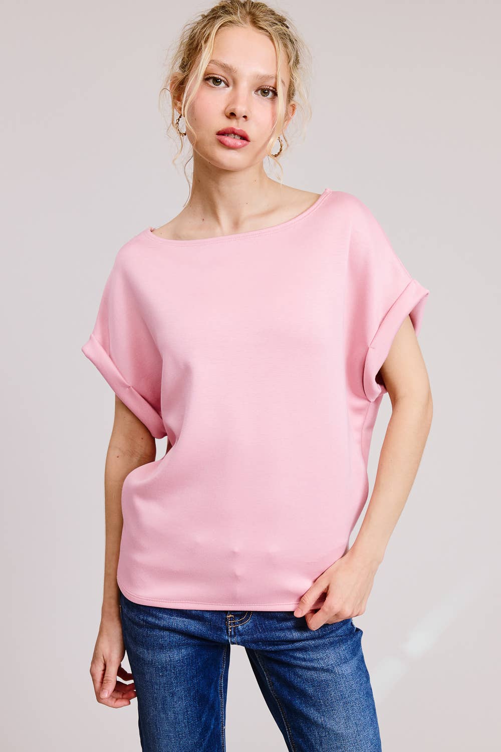 Woman wearing a pink top and blue jeans on a plain background