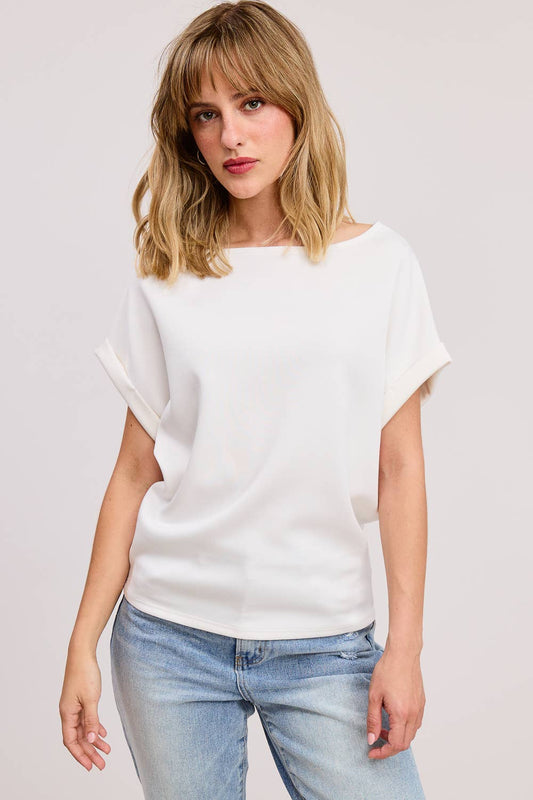Woman wearing a white top and light blue jeans on a plain background