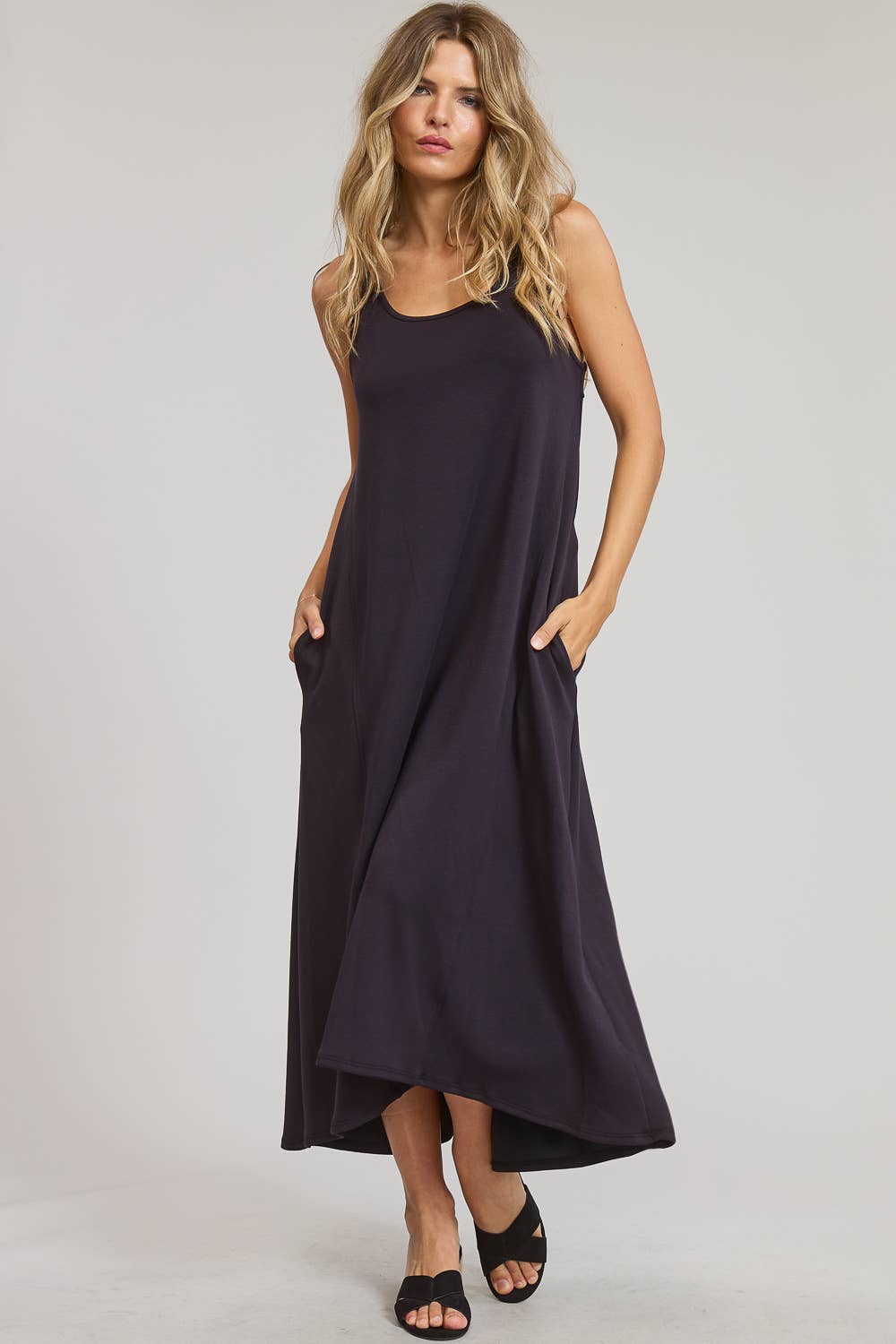 Woman wearing a black sleeveless dress on a plain background