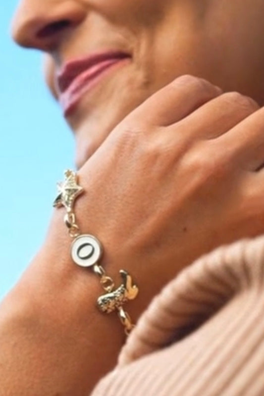 Close-up of a person wearing a bracelet with charms against a blurred background