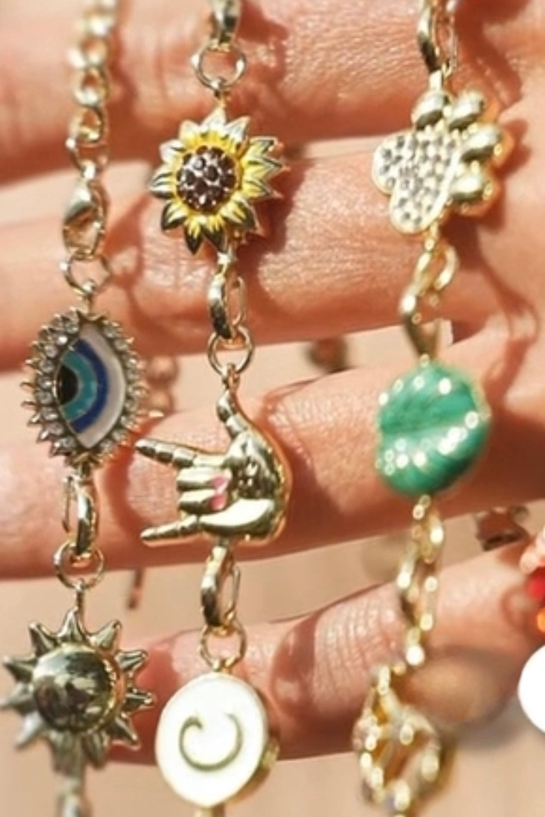 Gold charm bracelets with various charms on a hand.