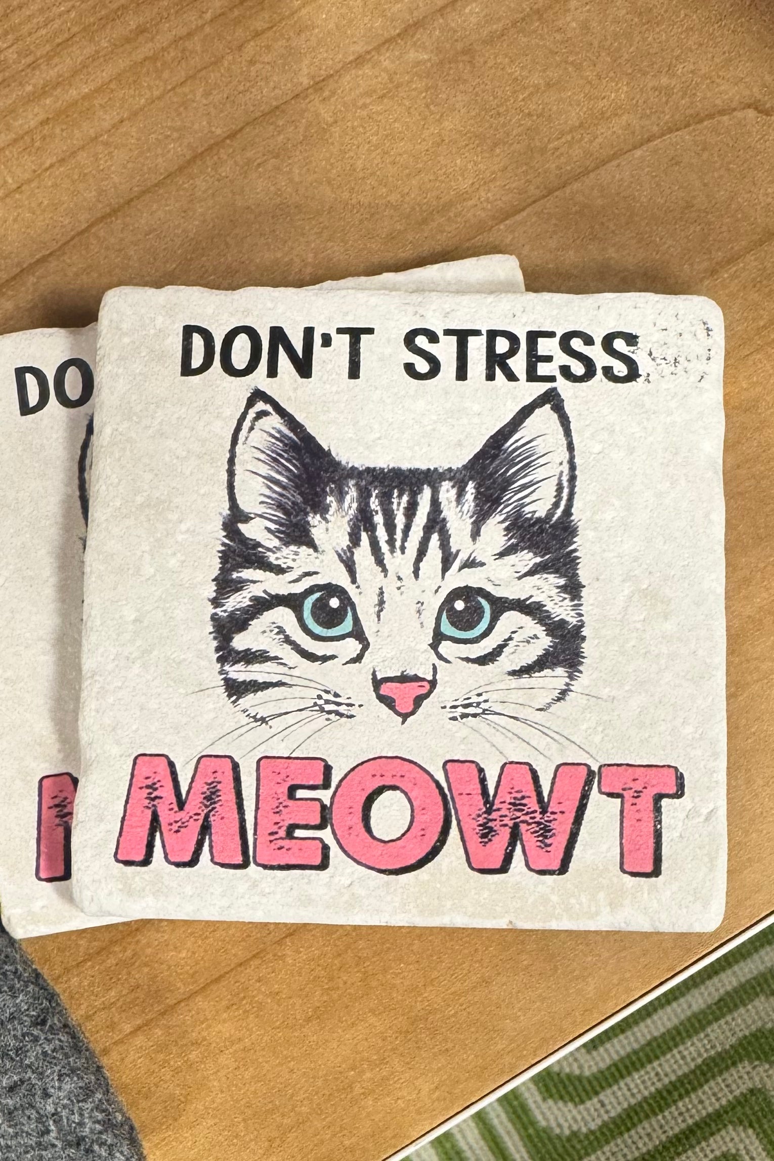 Coaster with a cat illustration and text 'Don't Stress I MEOWT' on a wooden surface.