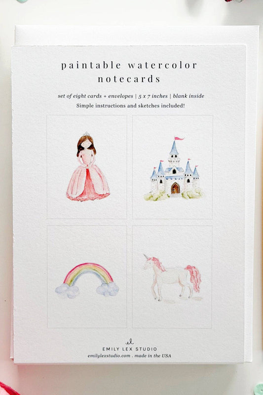 Set of paintable watercolor notecards with illustrations of a girl, castle, rainbow, and unicorn on a white background.