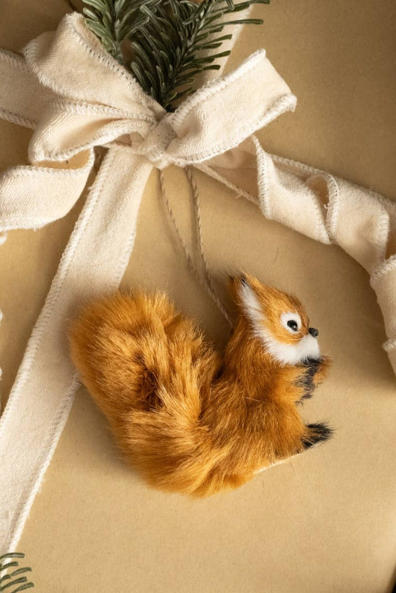 Gift wrapped in brown paper with a white ribbon and a small fox ornament.