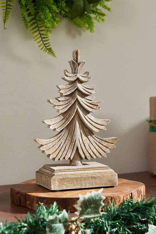 Decorative wooden Christmas tree on a wooden base with candles and greenery in the background.