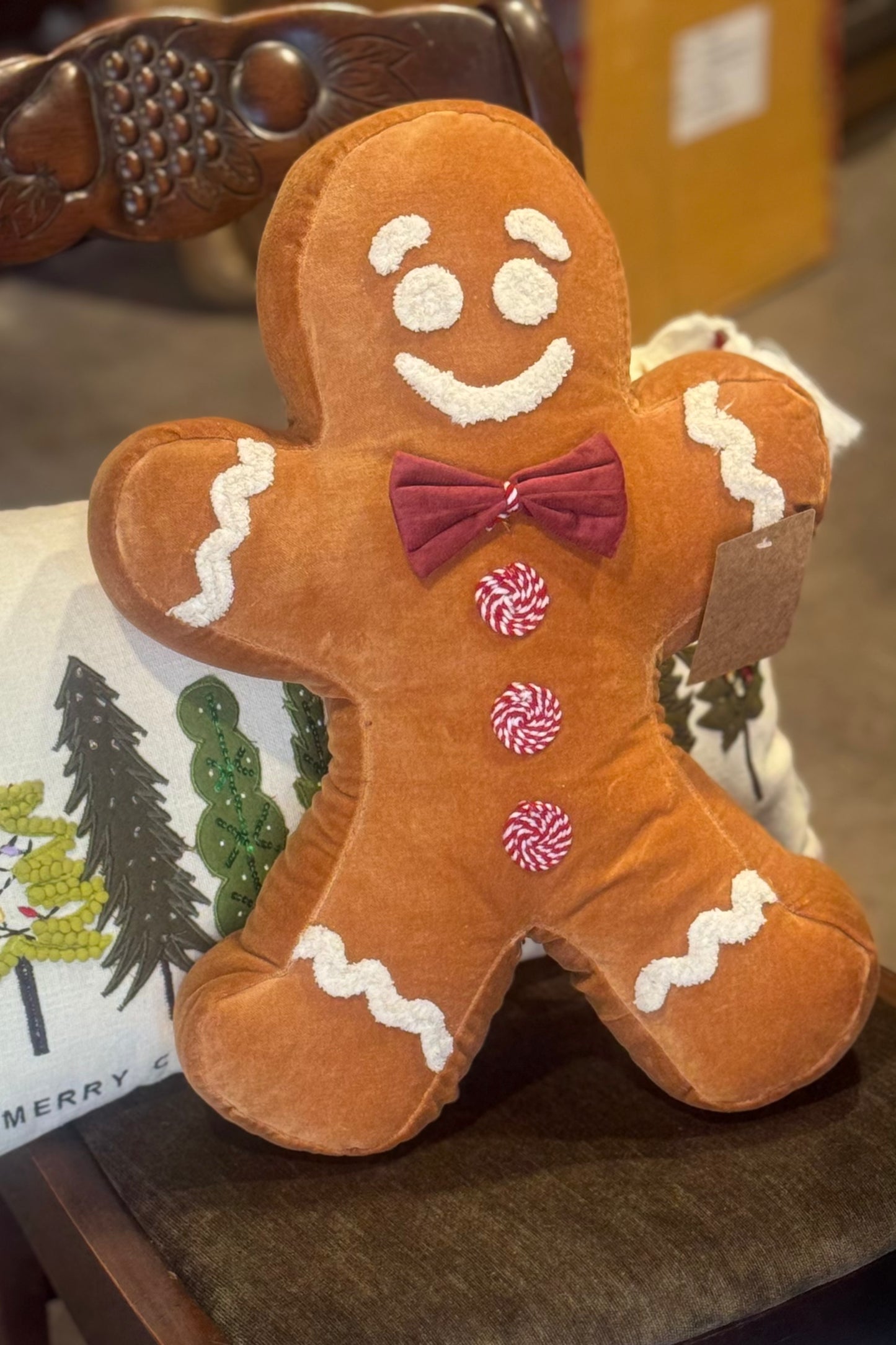 Plush gingerbread man pillow with a bow tie on a chair