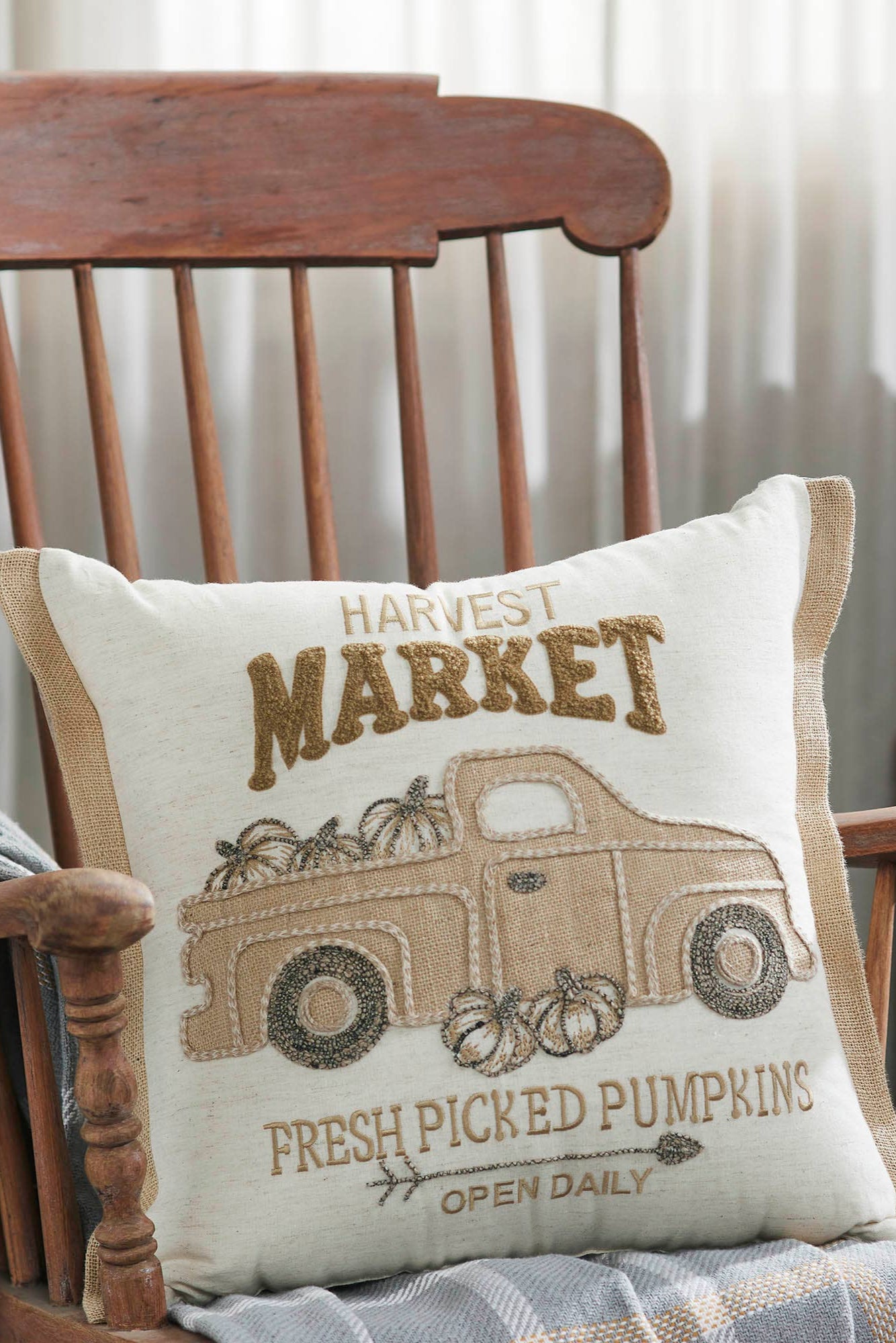 Decorative pillow with 'Harvest Market' design on a wooden chair.
