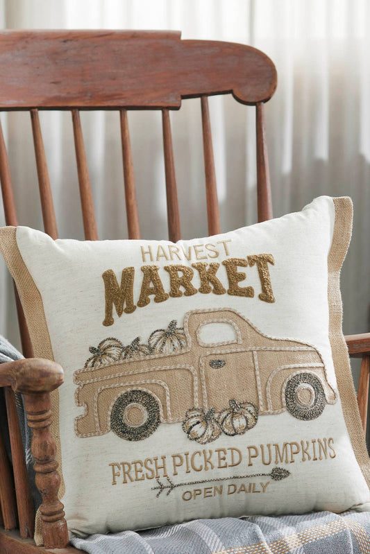 Decorative pillow with 'Harvest Market' design on a wooden chair.