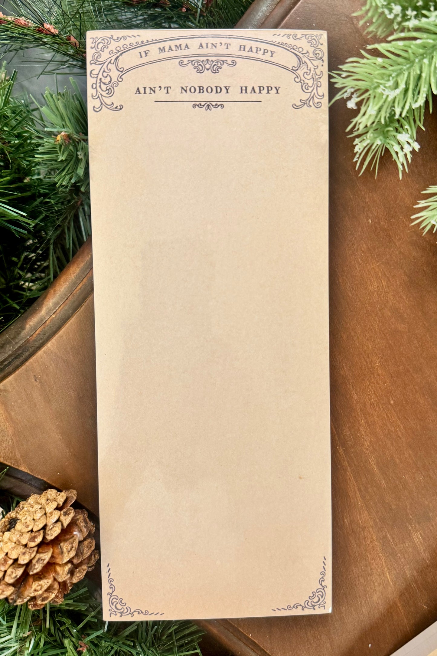 Notepad with decorative text on a wooden surface with greenery