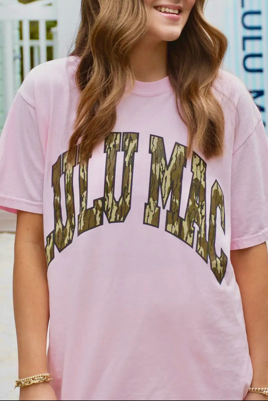Person wearing a pink t-shirt with 'Lulu Mac ' printed in camouflage letters.
