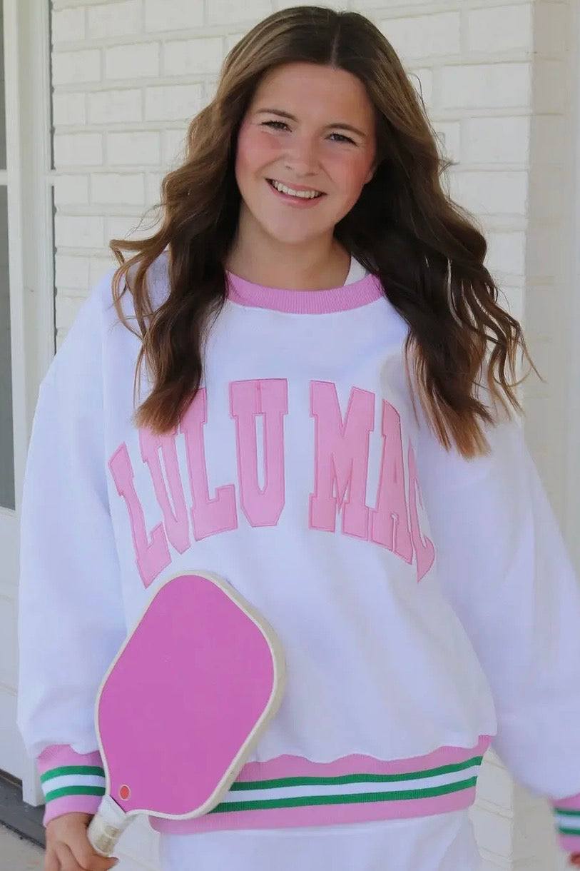 Person wearing a white sweatshirt with pink text and graphics