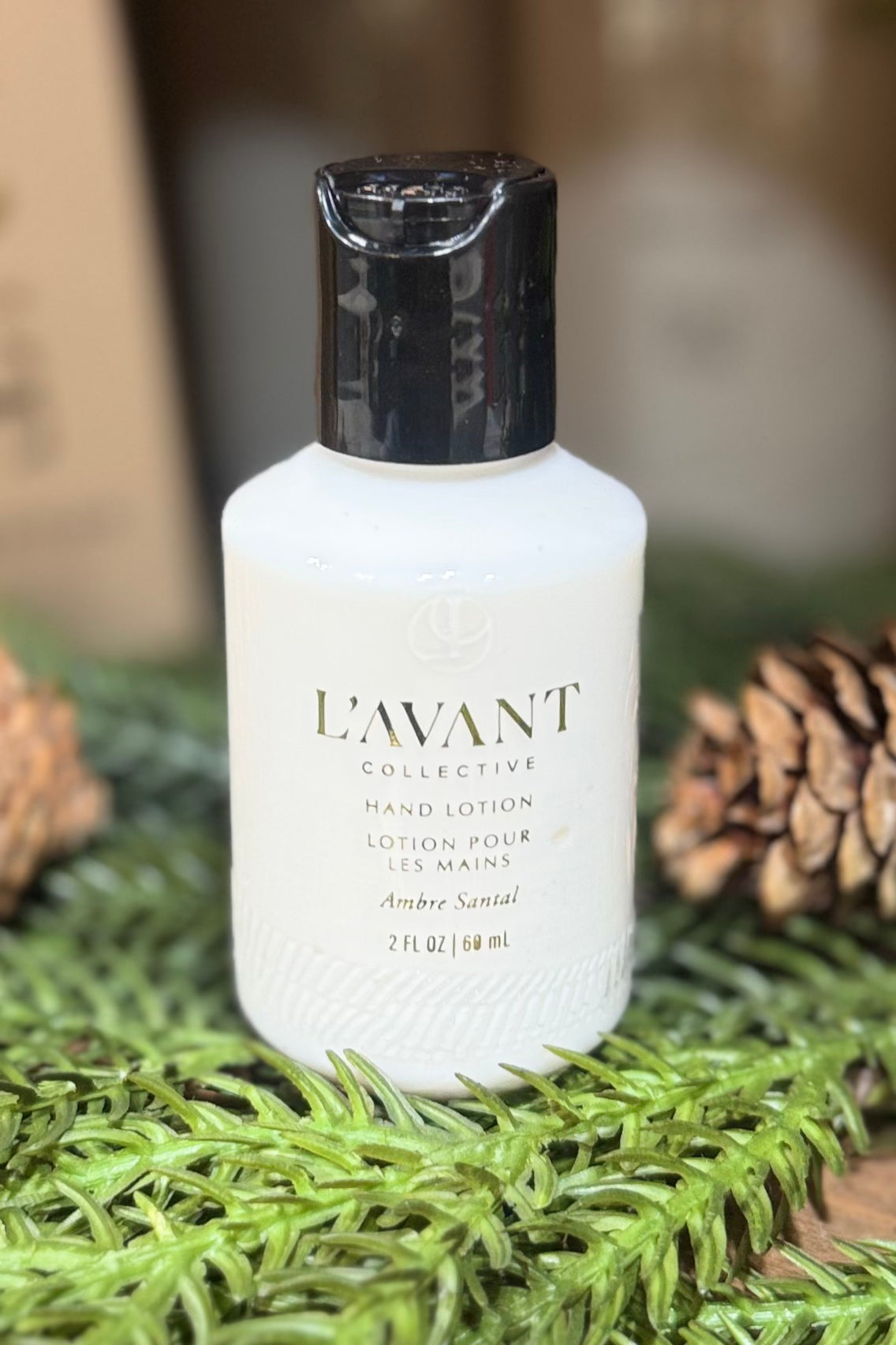 L'AVANT hand lotion bottle on a green surface with pine cones