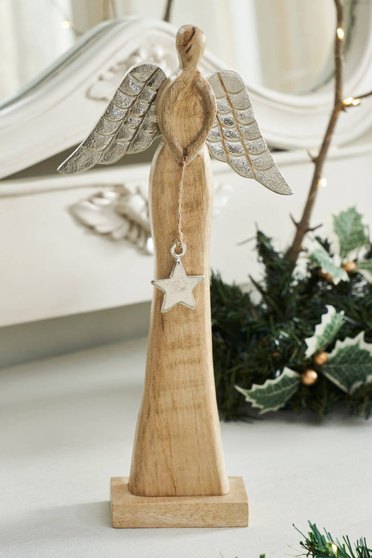 Wooden angel figurine with silver wings and star, placed on a surface with decorative elements.