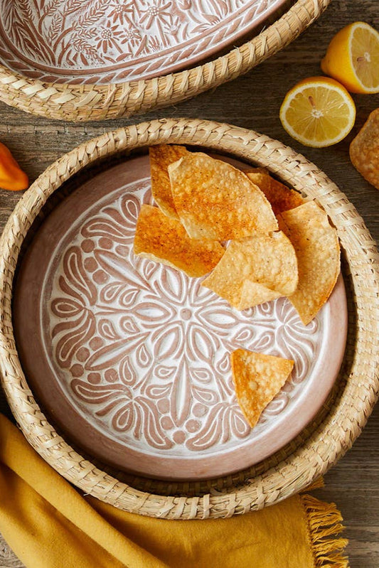 Decorative ceramic plates with embossed patterns and tortilla chips on a wooden surface.