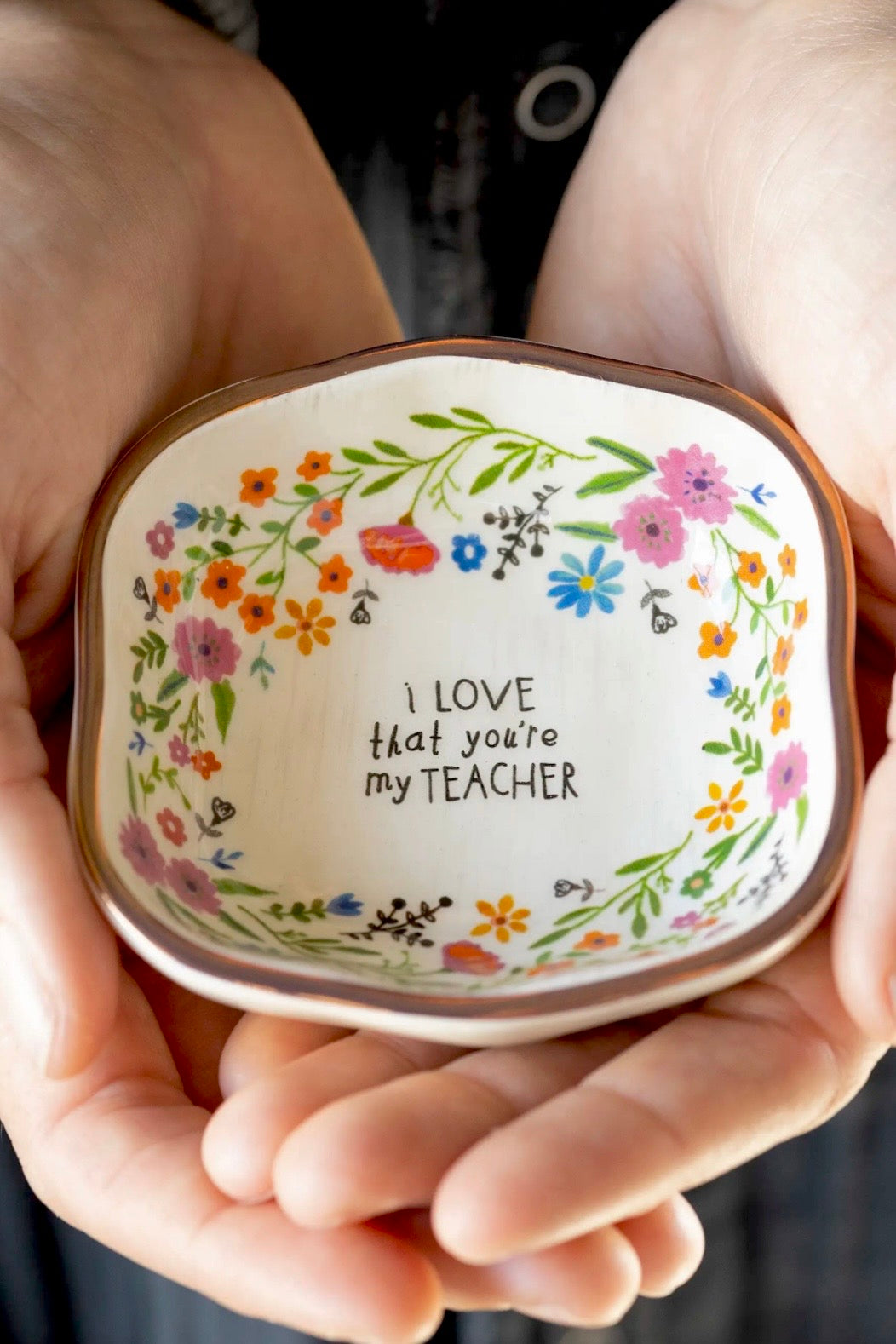 Decorative dish with floral design and text held in hands