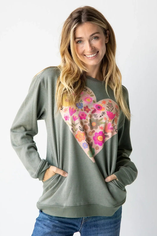 Woman wearing a green sweatshirt with a colorful heart design on a white background