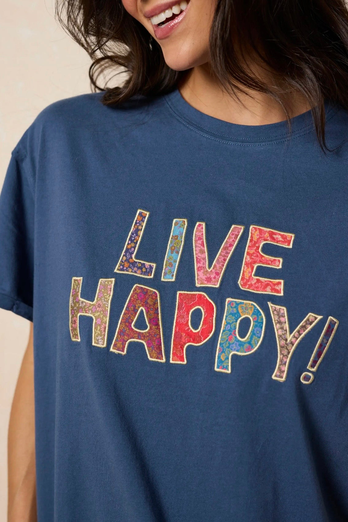 Navy blue t-shirt with 'LIVE HAPPY!' text in multicolor on a beige background
