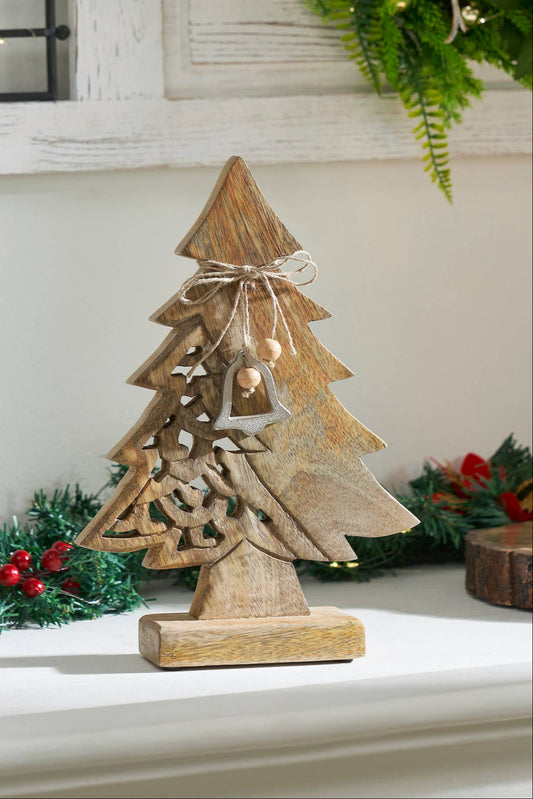Wooden Christmas tree decoration on a mantelpiece with candles and greenery.