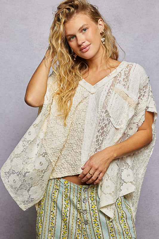 Woman wearing a lace top and patterned pants against a gray background