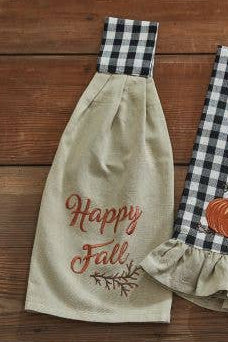 Two decorative towels with 'Happy Fall' text and a pumpkin design on a wooden surface.