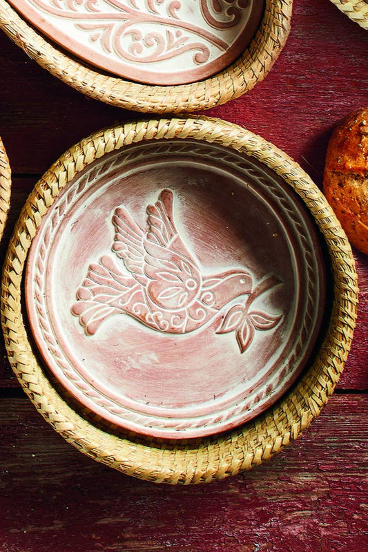 Decorative ceramic plate with bird design on a wooden surface with bread and jam.