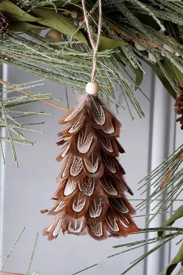 Pheasant feather ornament hanging among greenery with a white background