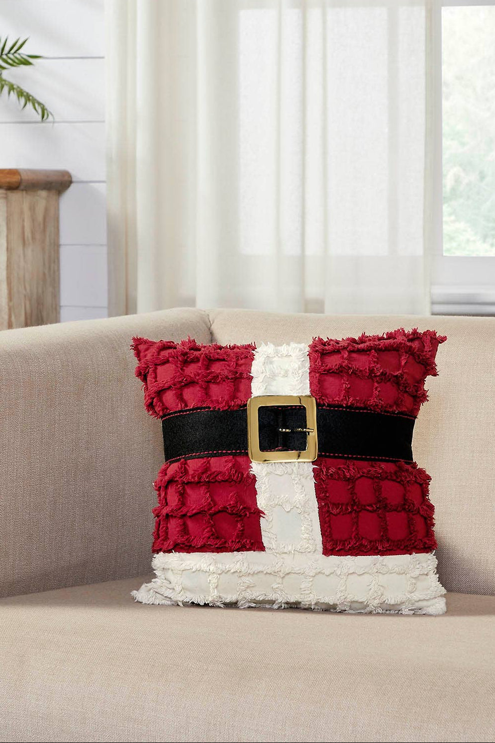 Decorative pillow with a festive design on a beige couch in a room with a wooden dresser and plants.