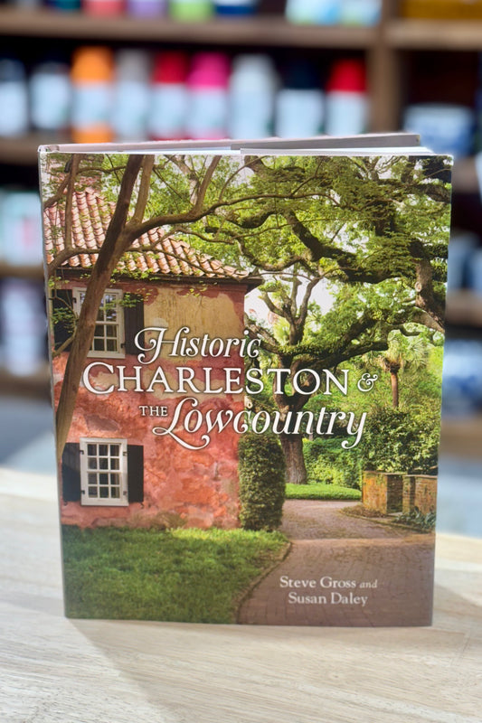 Book titled 'Historic Charleston & The Lowcountry' on a wooden surface with blurred bookshelf in the background.