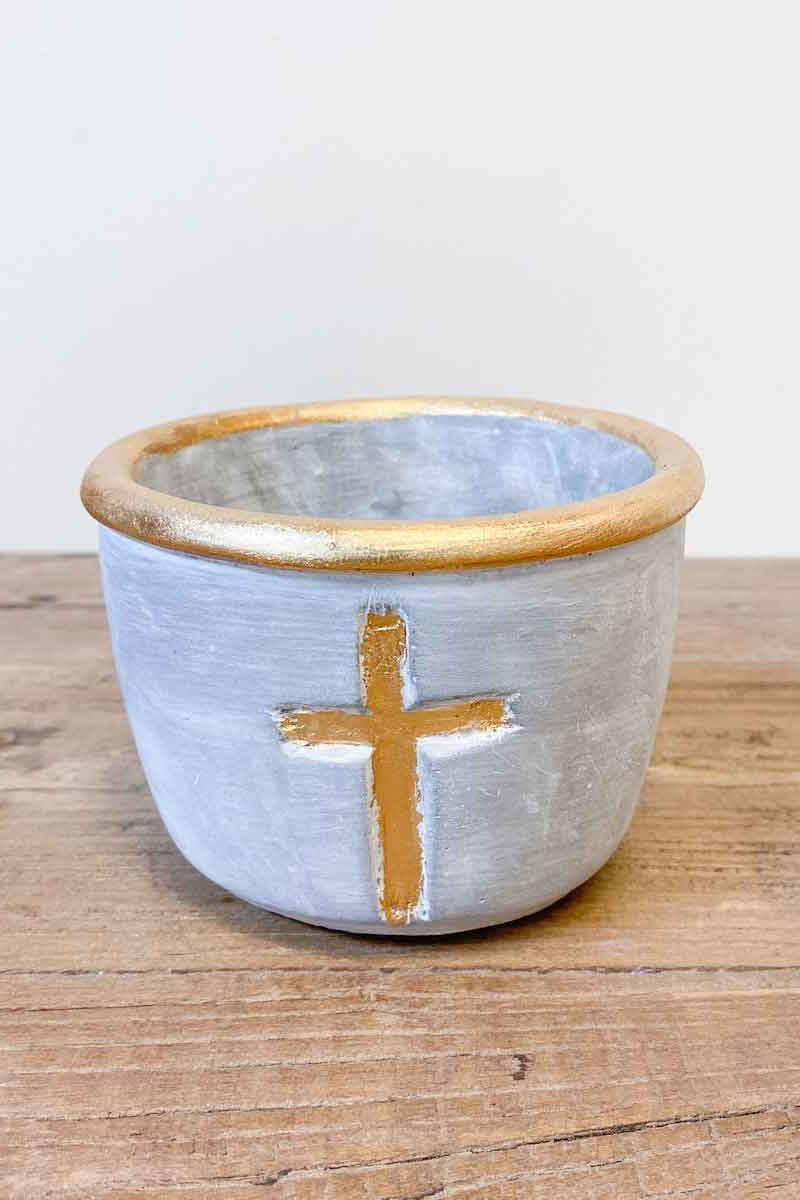 Ceramic pot with a gold cross on a wooden surface